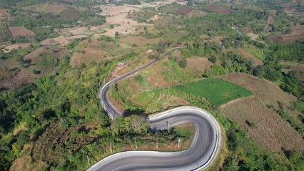 Wall Mural - Aerial view of a car running along the mountain road in countryside by drone