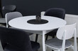 White wooden table complete with white and black wooden chairs with soft fabric upholstery. Black wax candle on the table.