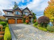 Photo of luxury home with a large stone brick driveway and wooden garage doors