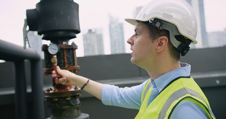 Canvas Print - A Engineer man looking inspecting maintenance insulated pipelines valve pump control on the roof at an industrial site, serious stressed face