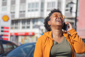 Wall Mural - smiling african american woman talking on smartphone on the street