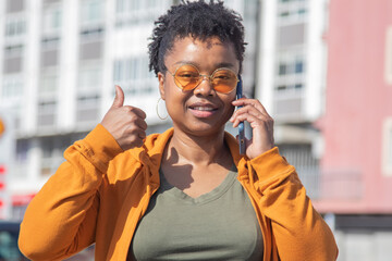 Wall Mural - african american woman talking with smartphone on the street and making ok sign