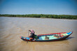 Woman riding boat along muddy river water in countryside