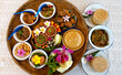 Northern Thai cuisine food set. Pork curry, chilli dip, minced pork salad, soft boiled vegetables and pork snack served in brass dishes. Decorated with flower, garland, spoon and basket background.