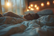 Young woman sleeping in bed at night in the light of garlands