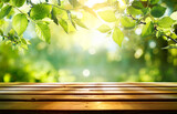 Fototapeta Kwiaty - Spring - Green Leaves On Wooden Table In Sunny Defocused Garden