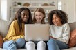 Young Teens Happiness. Multicultural Female Teens Cheerfully Sitting on Sofa, Smiling at Laptop