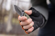 The man wearing tactical gloves using folding knife
