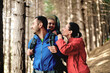 Family enjoys hike through the forest - young daughter happily seated in a child carrier backpack - joy of discovery and beauty of nature together.