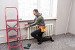 Worker replaces domestic radiator in the living room