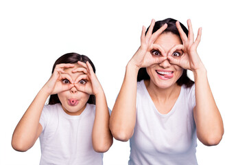 Close up photo beautiful two people brown haired mom little daughter friends look finger specs okey symbol tongue out mouth silly shapes figures wear white t-shirts isolated bright blue background