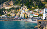 Fototapeta  - Amalfi on hills leading down to coast, comfortable beach and azure sea in Campania, Italy