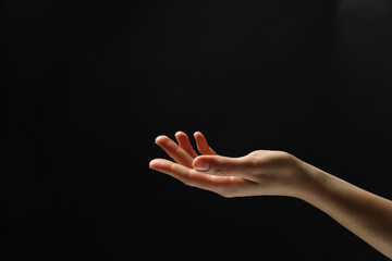 Wall Mural - woman holding something in hand on black background, closeup. space for text