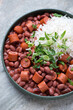 Plate of red beans with sausage and white rice on a light-grey granite surface, vertical shot, middle close-up