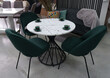White wooden table complete with green wooden chairs with soft fabric upholstery. Green cups on the table