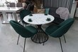 White wooden table complete with green wooden chairs with soft fabric upholstery. Green cups on the table