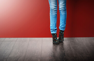 Poster - Fashion, jeans and legs of woman in studio with stylish clothes standing on red background. Trendy, edgy and fashionista in modern outfit, cool style or denim for crazy socks day on floor or ground