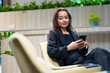 © NVB Stocker - Mobile phone technology lifestyle - Hispanic business woman uses mobile phone device communicating with colleague relaxing on sofa at modern office building