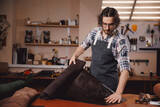 Fototapeta  - Leather artisan cobbler working with leather textile product in workshop, sunlight