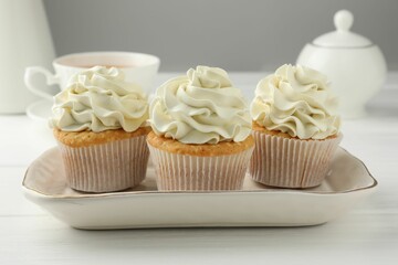 Tasty cupcakes with vanilla cream on white wooden table, closeup