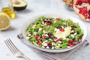 Wall Mural - A plate with green rocket salad with pomegranate and avocado