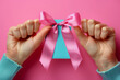 Hands Proudly Presenting a Small Turquoise Box with a Pink Satin Ribbon on Pink Background