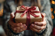 Close-up of Hands Holding a Wrapped Gift with a Red Glitter Ribbon and Soft Bokeh