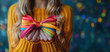 Hands Holding Colorful Satin Ribbons Tied into a Bright Bow, Blue Yellow Concept