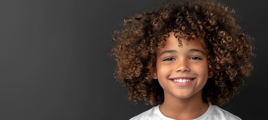 Wall Mural - Young girl with beautiful curly hair happily smiling while making eye contact with the camera