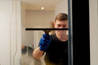 © Guys Who Shoot - in an apartment cleaner in a yellow apron is cleaning windows with a rubber brush