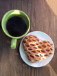Heart-shaped cookie and green cup with coffee