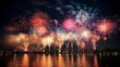  Bright fireworks light up the dark night sky above a body of water, creating a colorful spectacle.