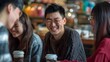 © pkproject - Asian Friends Sharing Laughter and Conversation Over Coffee in Cozy Cafe