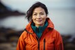 © Markus Schröder - Portrait of a content asian woman in her 40s donning a durable down jacket isolated on stunning ocean reef