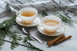 Two white ceramic cups with black tea and cinnamon sticks