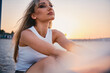 Serene woman in white enjoying a golden sunset, exuding a sense of calm and elegance against an evocative backdrop