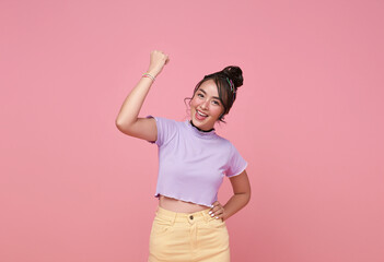 Happy Asian woman excited overjoyed standing with raised fists and shouting yeah, I'm winner, rejoicing victory, success isolated on pink background.