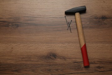 Sticker - Hammer and metal nails on wooden table, top view. Space for text