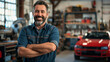 © Kowit - A man is smiling in a garage with a red car behind him. Scene is happy and positive