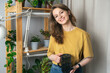Young woman watering indoor plants in her house. Beautiful young woman taking care of house flowers in her flat. Jungle concept in her home.