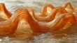   A tight shot of an undulating orange object submerged in water, with water beads clinging to its base and the upper half of the wavy form positioned centrally