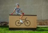 Fototapeta  - Grinning teenager cyclist posing on large bike-icon package