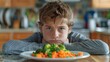 © Iuliia Metkalova - Unhappy grumpy teenage boy sitting in front of plate with healthy green food in kitchen at home. Children healthcare concept. Generative ai