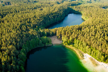 Aerial view of beautiful green waters of lake Gela. Birds eye view of scenic emerald lake surrounded by pine forests. Clouds reflecting in Gela lake, Lithuania.