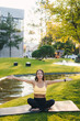 © Strelciuc - Full length view of an adult woman in sports leggings and top doing arms stretch in public park in sun. Healthy active lifestyle, sports, outdoor fitness