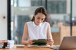 © amnaj - A professional woman in a sleeveless white blouse sits at her desk reviewing a document.