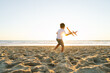 © Koldo_Studio - A boy runs with a toy plane against a sunset