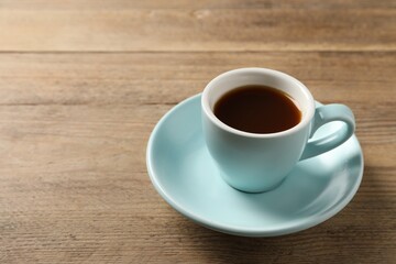 Poster - Tasty coffee in cup on wooden table, closeup. Space for text