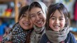 A mother and her two daughters are smiling at the camera. The mother is wearing a brown hijab. The daughters are wearing winter clothes.