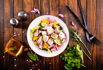 Wall Mural - Greek salad of fresh cucumber, tomato, sweet pepper, lettuce, red onion, feta cheese and olives with olive oil. Healthy food, top view